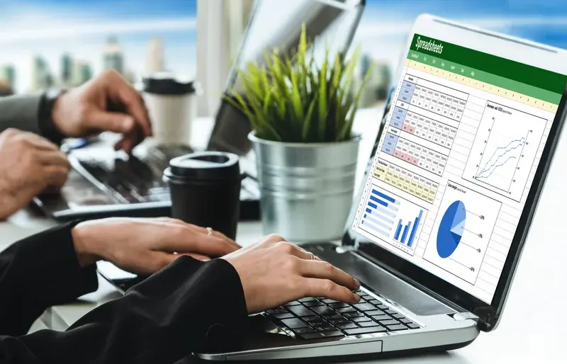 Persona trabajando en una laptop con hojas de cálculo y gráficos de un plan de cuenta